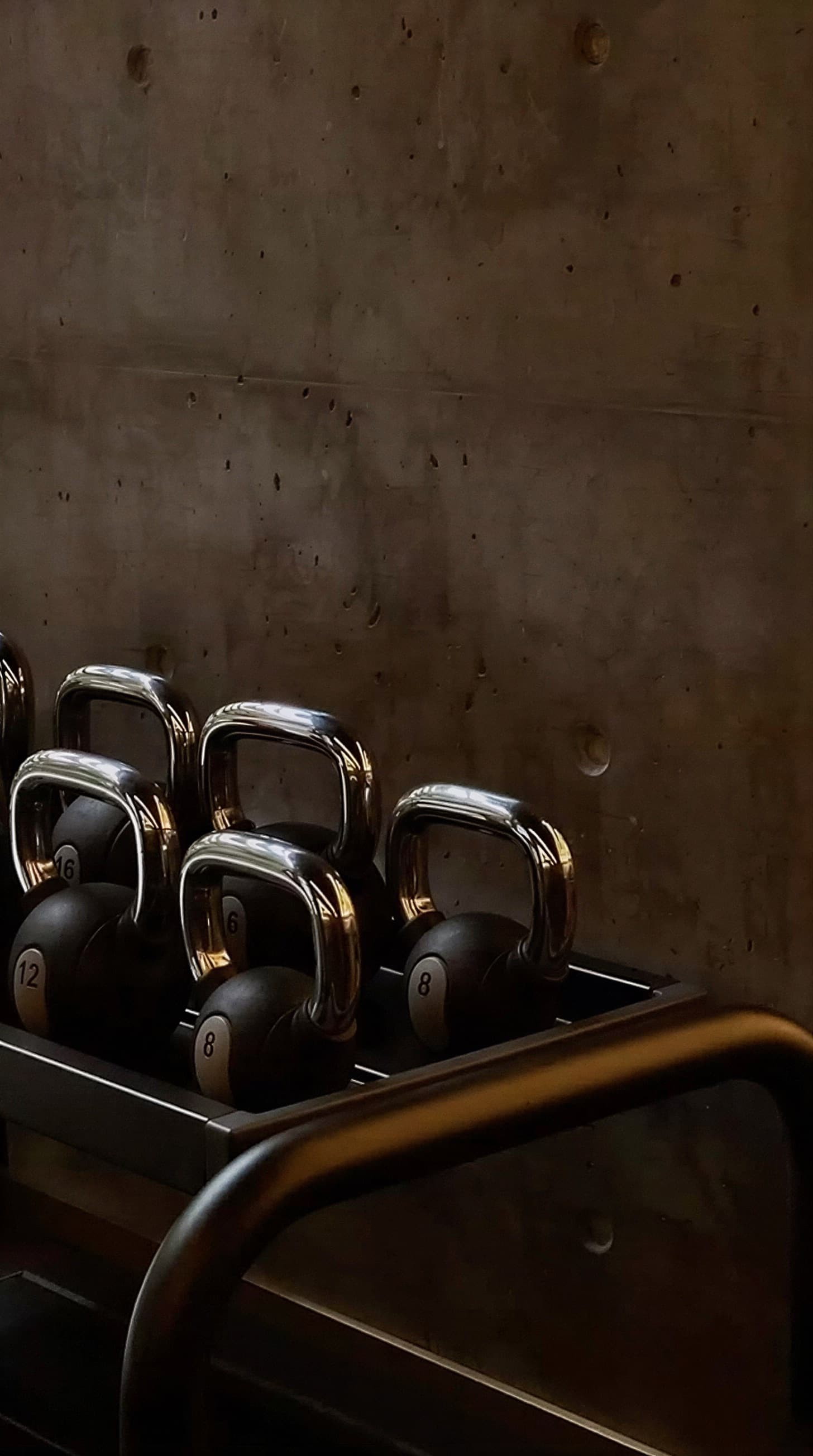 Movement studio with a kettlebell rack against a concrete wall